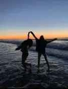 Deux personnes dansent au bord de la mer au coucher du soleil.